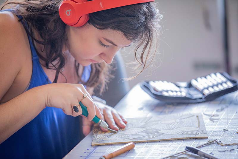 A student focused as she works on her printmaking square, with her Meredith ring on her right hand.