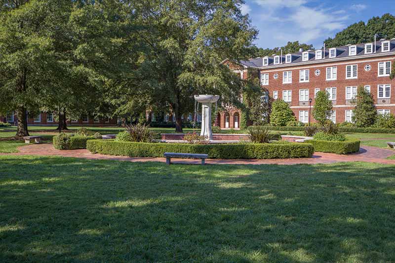 View of the courtyard showing the fountain and a dorm behind it.