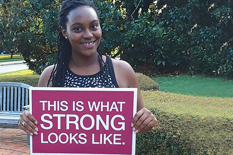 Destiny McDuffie holding sign reading this is what strong looks like.