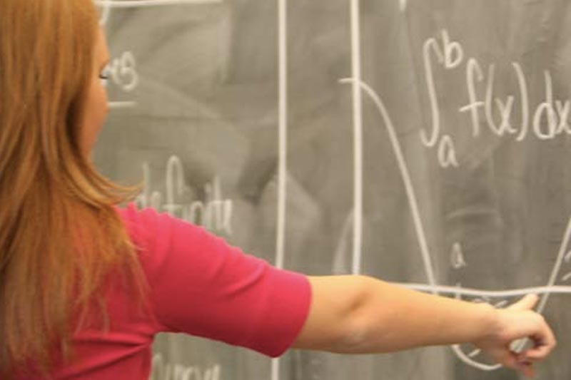 Student Writing Equation on Chalkboard