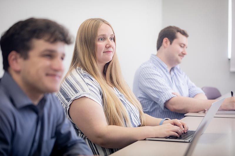 Two male students and one female student pay attention during class in I-O Psych.