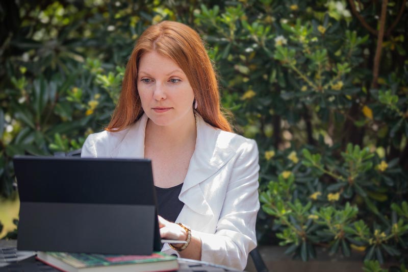 Transfer student sitting outside looking at tablet.