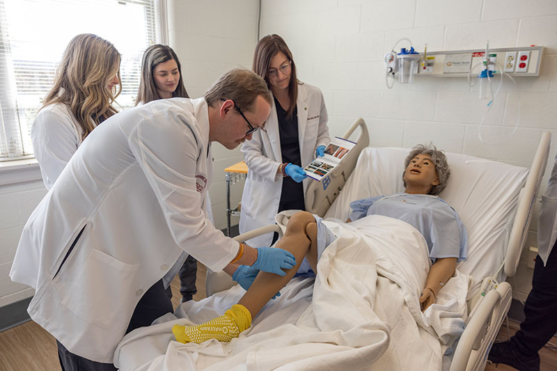 MSN Students doing vital check on dummy in Lab scenario
