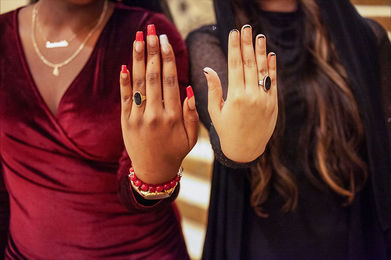 Two Students holding hand up to show onyx ring on fingers.
