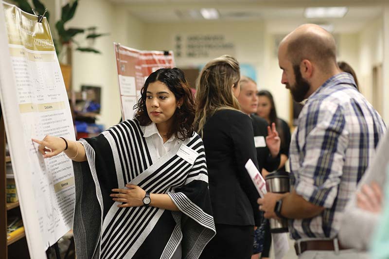 student explaining poster presentation